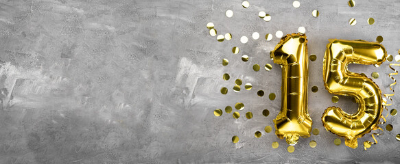 Yellow foil balloon number, number fifteen on a concrete background. 15th birthday card....