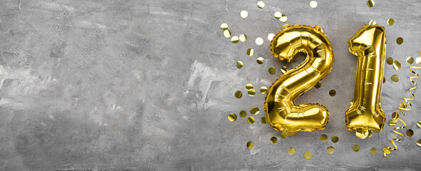 Yellow foil balloon number, number twenty one on a concrete background. Birthday card with...