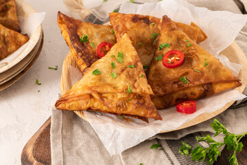 Indian samosas - fried or baked pastry with savoury filling, popular Indian snacks, served with yogurt sauce in areca leaf dishes with spices on kitchen countertop.