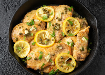 Chicken Piccata with capers, white wine sauce in iron cast pan. Italian food