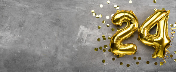 Yellow foil balloon number, number twenty-four on a concrete background. 24th birthday card....