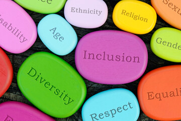 Inclusive words on colorful wooden stones. Diversity in community and work culture concept. - obrazy, fototapety, plakaty