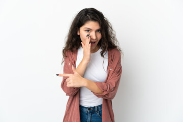 Teenager Russian girl isolated on white background pointing to the side to present a product and whispering something