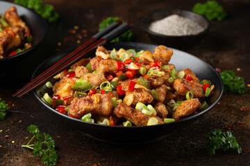 Stir fry salt and pepper pork loin with herbs in black bowl. Asian food