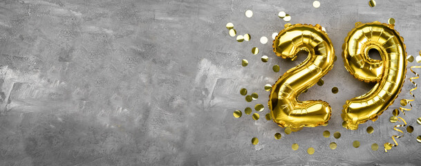 Yellow foil balloon number, number twenty nine on a concrete background. Birthday card with inscription 29. Anniversary concept. for anniversary, birthday, new year celebration.