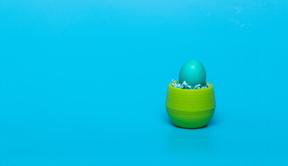 blue egg in a green jar on a blue background