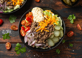 Cheeseburger, hamburger or burger keto salad with beef, fresh tomatoes, red onion, pickled gherkins, lettuce and home made sauce dressing