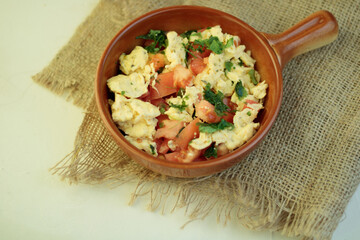 Scrambled egg in frying pan and toast on wooden table