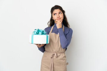 Pastry Russian chef holding a big cake isolated on white background having doubts