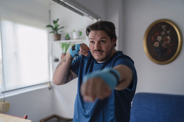 hombre con camiseta azul y cintas elásticas en las manos practicando deporte en casa