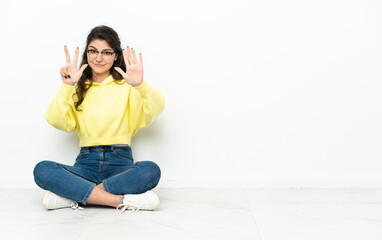 Teenager Russian girl sitting on the floor counting eight with fingers