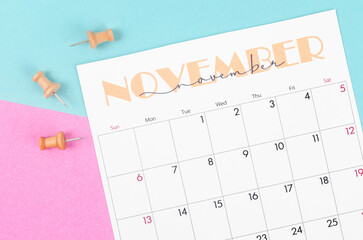 November 2022 calendar and wooden push pin on beautiful background.