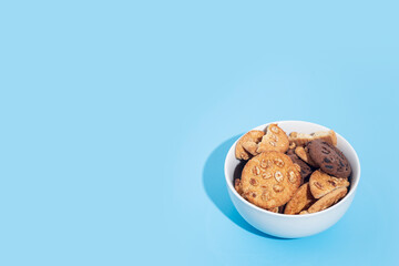 Cookies in a white bowl, blank space for text on a light blue background.