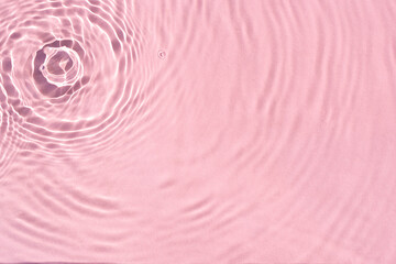 Fototapeta na wymiar Texture wave from drops on pink water under sunlight. Top view, flat lay