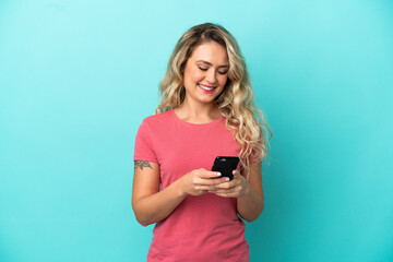 Young Brazilian woman isolated on blue background sending a message or email with the mobile