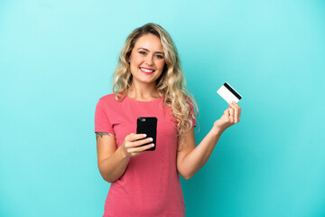 Young Brazilian woman isolated on blue background buying with the mobile with a credit card