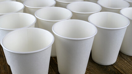 Row of white disposable eco friendly paper cup for coffee or hot beverage on dark backdrop. Selective focus. - 493775422