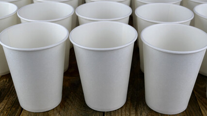 Row of white disposable eco friendly paper cup for coffee or hot beverage on dark backdrop. Selective focus. - 493775425