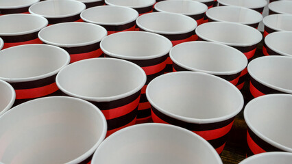 Row of red and black disposable eco friendly paper cup for coffee or hot beverage on dark backdrop. Selective focus. - 493775438