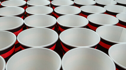 Row of red and black disposable eco friendly paper cup for coffee or hot beverage on dark backdrop. Selective focus. - 493775444