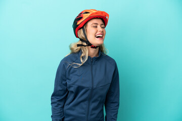 Young cyclist woman isolated on blue background laughing