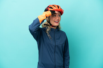 Young cyclist woman isolated on blue background doing surprise gesture while looking to the side