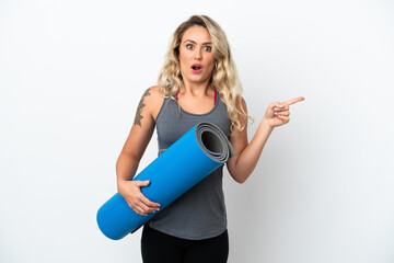 Young sport Brazilian woman going to yoga classes while holding a mat isolated on white background...