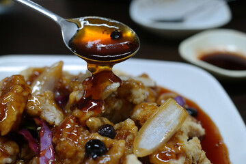 Add sweet and sour pork sauce with a spoon.