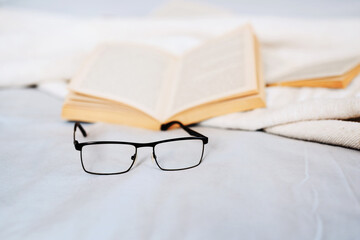 A good read starts with good reading glasses. Still life shot of reading glasses and books lying on a bed.