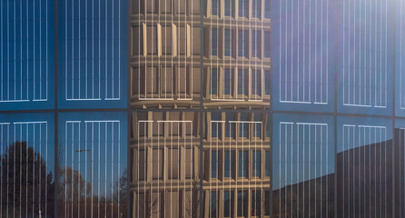 close up of a Facade with integrated solar panels, reflecting a modern office building and blue...