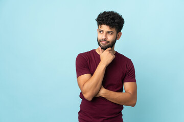Young Moroccan man isolated on blue background and looking up