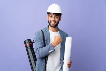 Young architect Moroccan man with helmet and holding blueprints over isolated background...