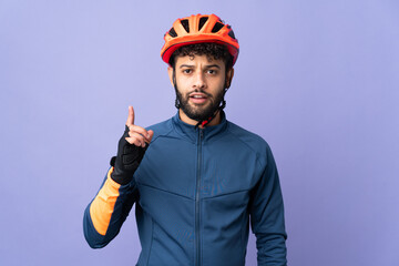Young Moroccan cyclist man isolated on purple background thinking an idea pointing the finger up