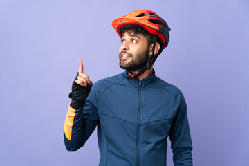 Young Moroccan cyclist man isolated on purple background pointing up a great idea - obrazy, fototapety, plakaty