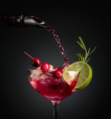 Cranberry cocktail garnished with berries, lime, and rosemary.