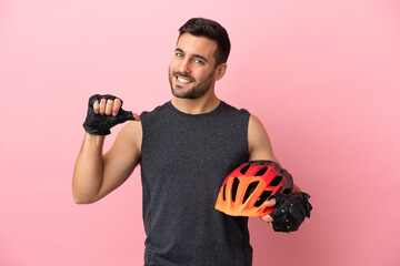 Young cyclist man isolated on pink background proud and self-satisfied - obrazy, fototapety, plakaty