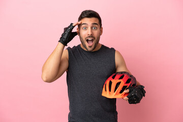 Young cyclist man isolated on pink background with surprise expression - obrazy, fototapety, plakaty