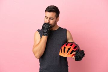 Young cyclist man isolated on pink background having doubts - obrazy, fototapety, plakaty