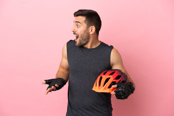 Young cyclist man isolated on pink background with surprise expression while looking side - obrazy, fototapety, plakaty