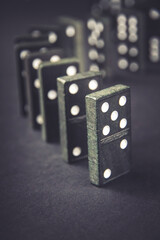 Black dominoes chain on dark table background