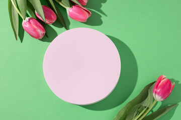 Pink podium for product display on green with tulips flowers in hard light