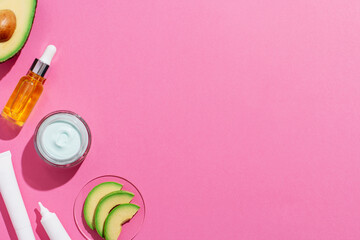 Avocado skin care cosmetics flat lay frame on pink