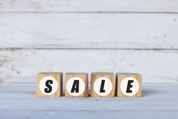sale concept written on wooden cubes or blocks, on white wooden background.