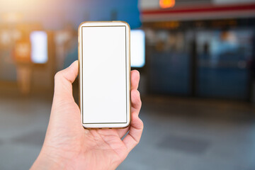 Hand holding smart phone with blank screen for mockup while waiting for the bus