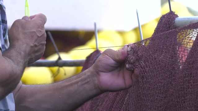 4K close-ups of fishermen mending their torn nets.