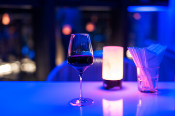A glass of red wine on bar table with blur light bokehin restaurant