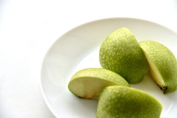 Green apple slices on a white plate