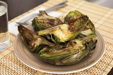 cooked fried halves artichokes on brown plate