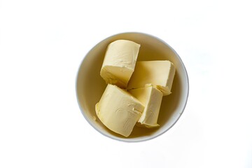 Top view butter pieces in bowl, isolated on white background