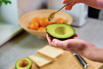 Woman hold fresh ripe avocado and peeling it with spoon, Healthy food and dieting concept, Organic product